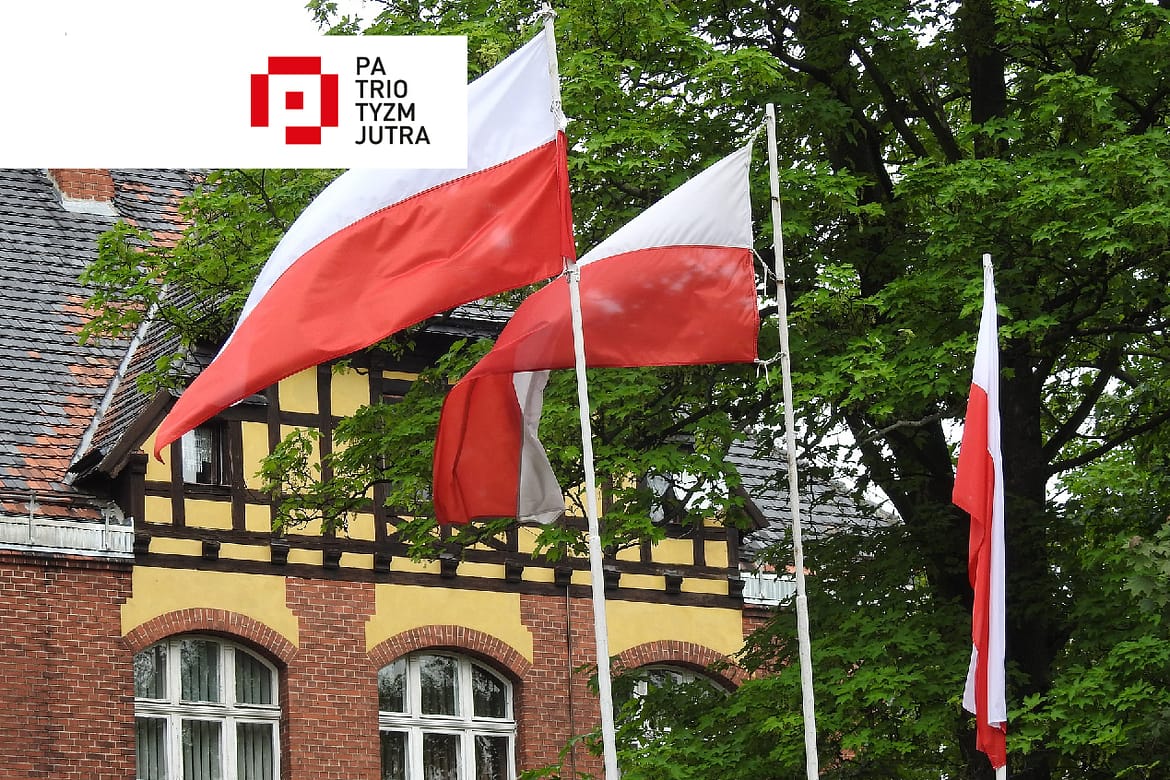 flagi Polski na tle budynku wraz z logo programu Patriotyzm Jutra